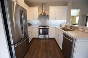 A newly remodeled kitchen with stainless steel appliances, white cabinetry, and a stylish backsplash